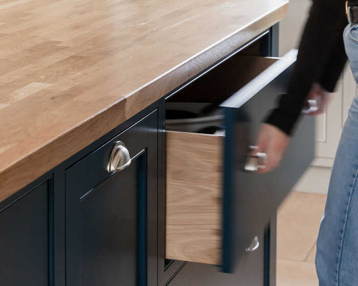 lady opening a bespoke kitchen cabinet draw integrated into a kitchen island with a wooden countertop lady opening a bespoke kitchen cabinet draw integrated into a kitchen island with a wooden countertop